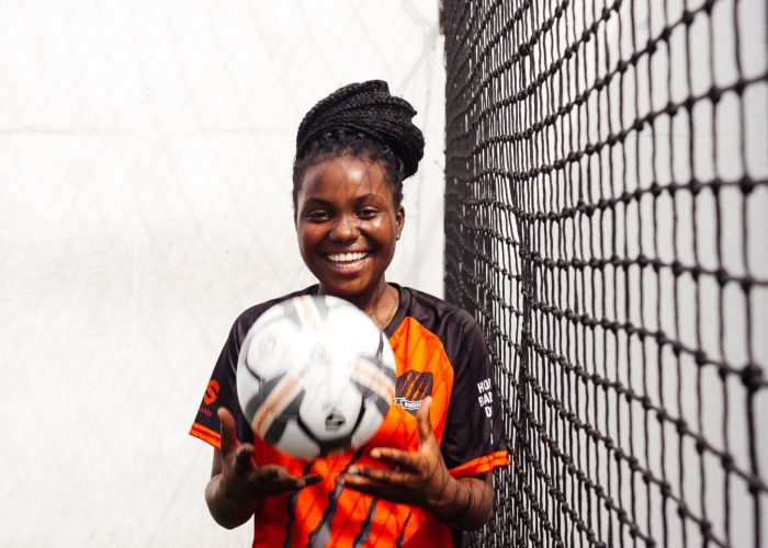 smiling-girl-in-black-and-orange-uniform-holding-soccer-ball-3886257